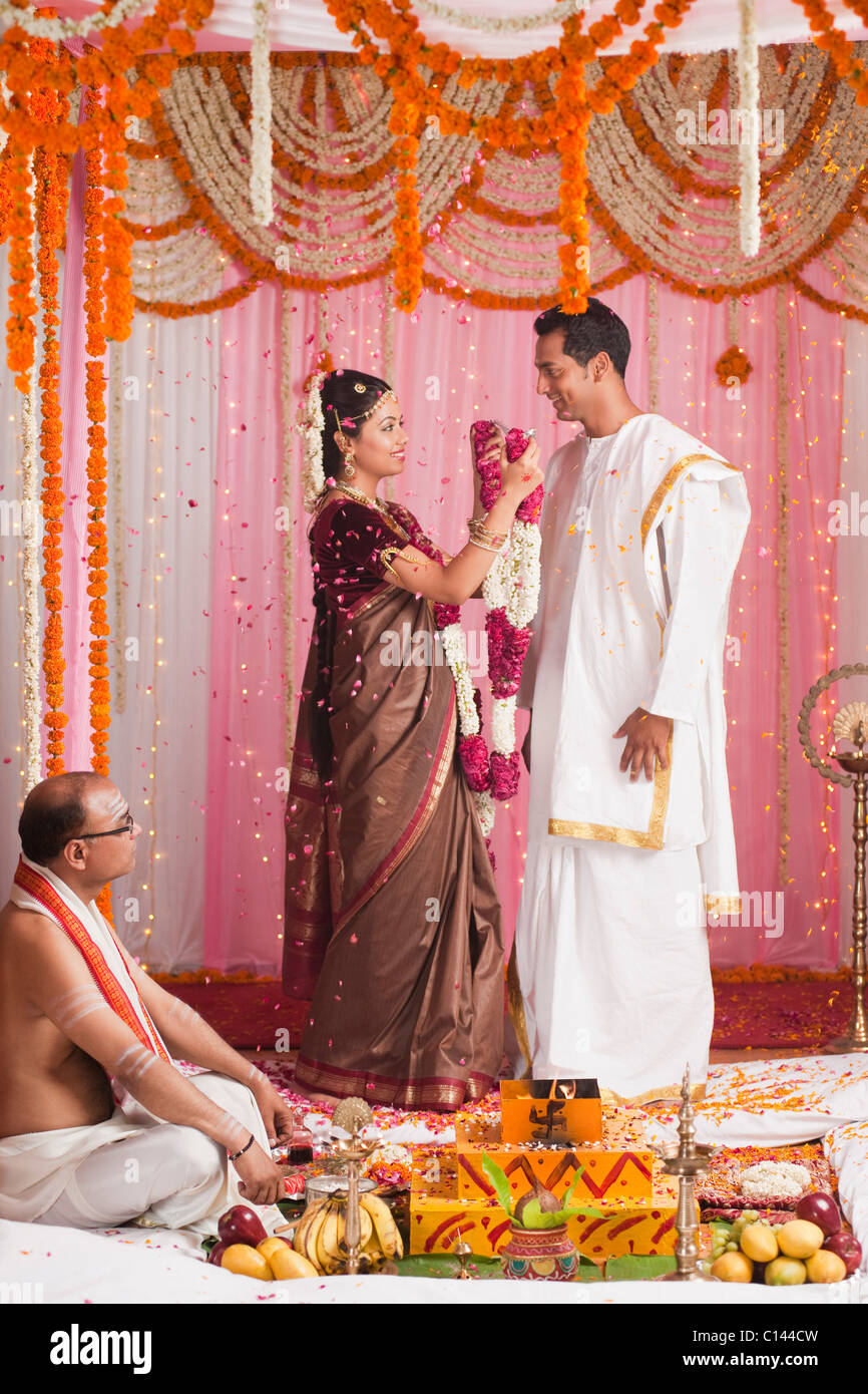 Sposa di mettere la ghirlanda di uno sposo durante il sud indiana cerimonia di nozze Foto Stock