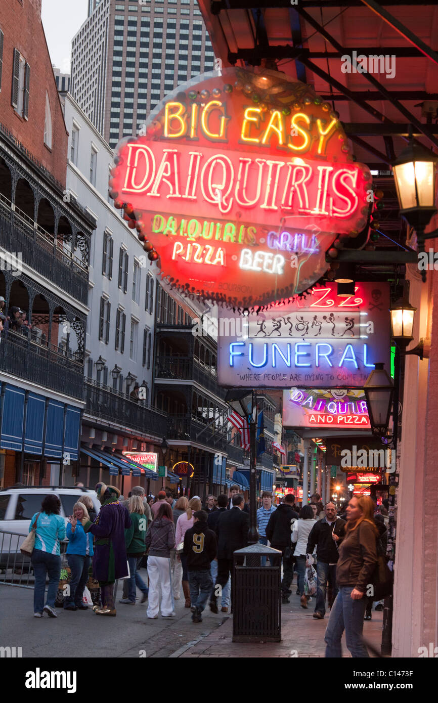 Persone che camminano da insegne al neon per i bar e i club lungo Bourbon Street a New Orleans di notte Foto Stock