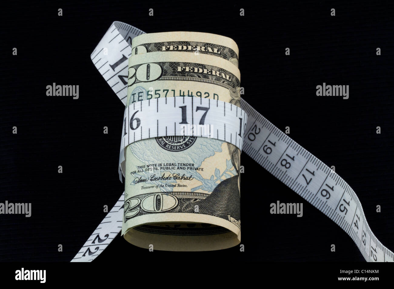 Moneta americana con un nastro di misurazione intorno ad esso contro lo sfondo nero; immagine di analisi finanziaria e di valutazione. Foto Stock