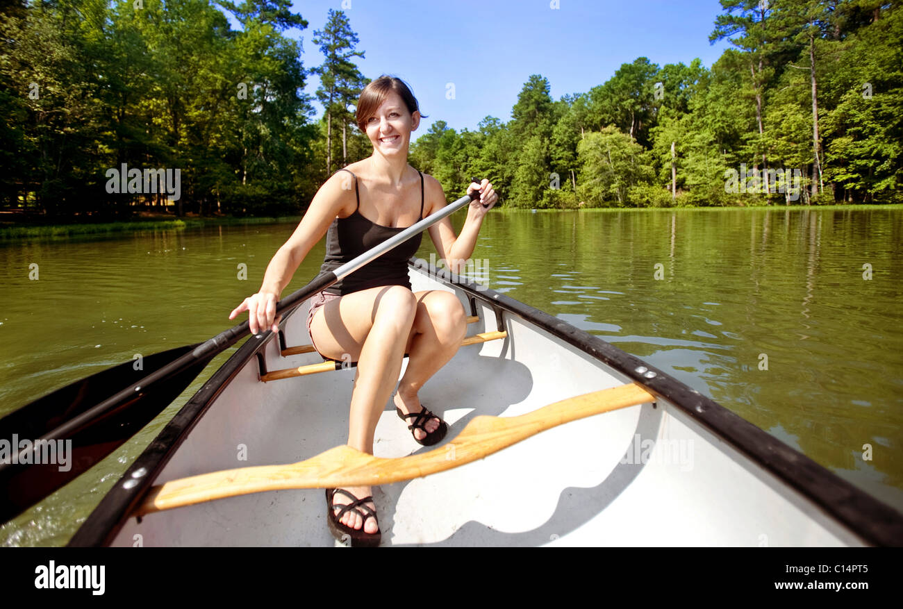 Giovane donna sorridente mentre canoa da soli su un lago a Oak Mountain State Park, Pelham, AL. Foto Stock