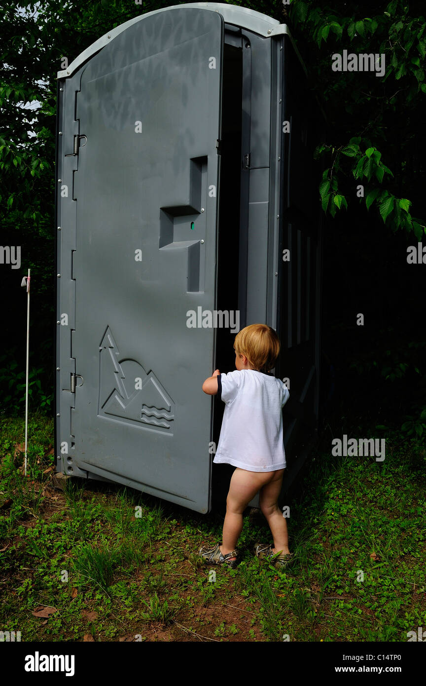 Ragazzo giovane apre il portello sul WC portatili Foto Stock