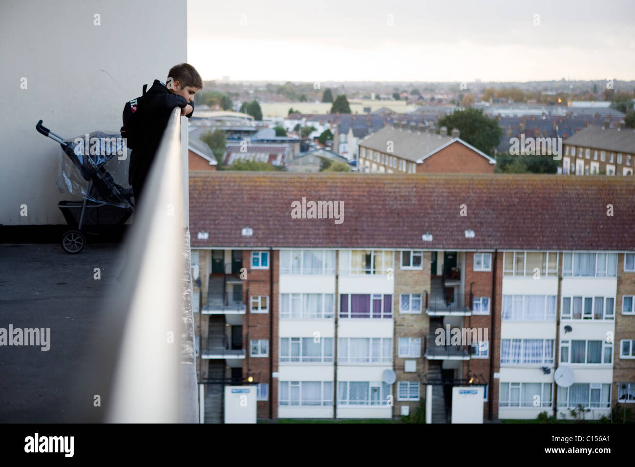 Ragazzo che guarda oltre il balcone sul complesso residenziale nella zona est di Londra Foto Stock