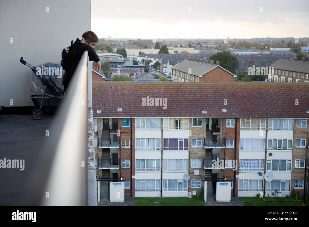 Ragazzo che guarda oltre il balcone sul complesso residenziale nella zona est di Londra Foto Stock