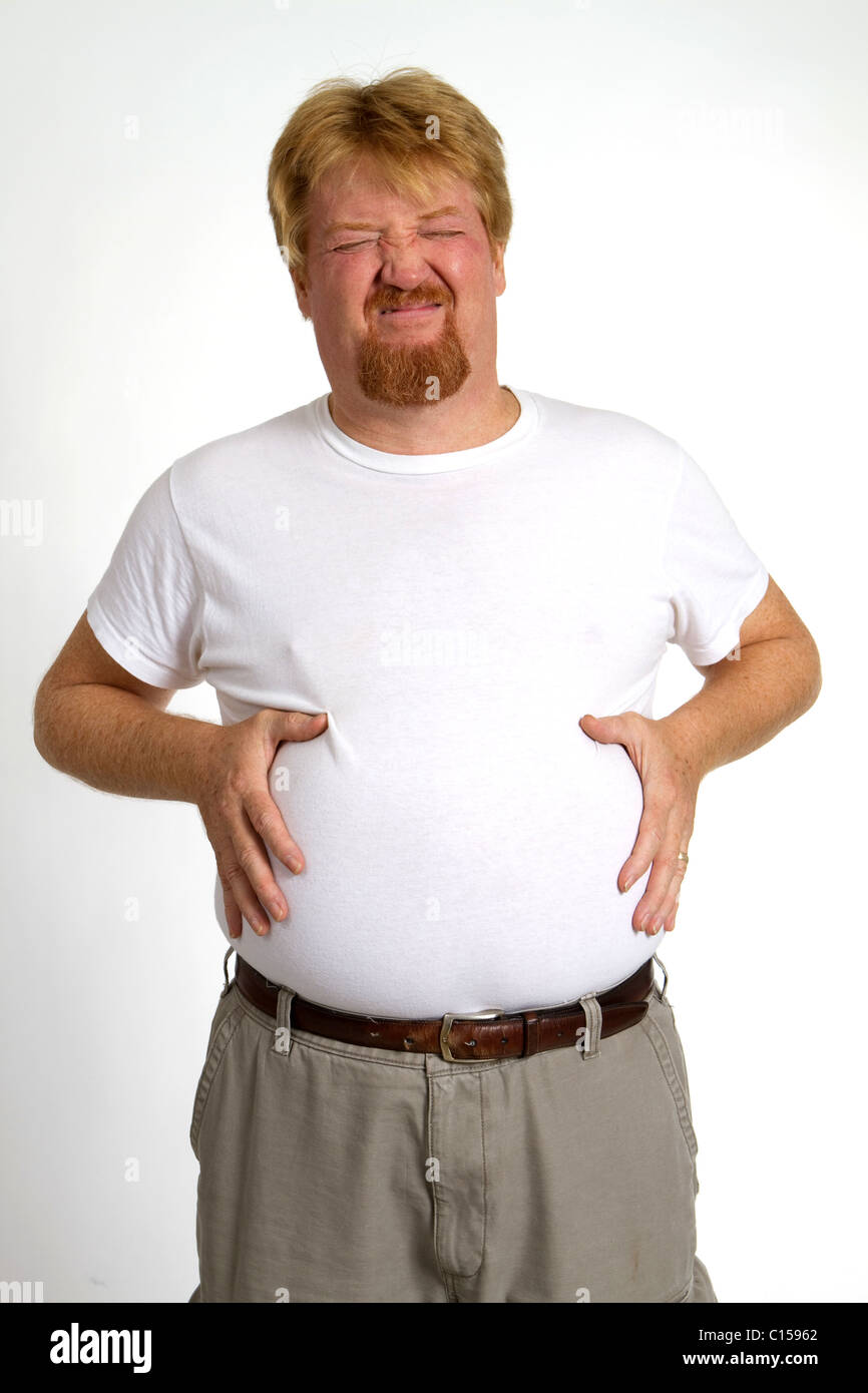 Il sovrappeso uomo con indigestione da surriscaldamenti tiene il suo stomaco con disagio e dolore. Foto Stock