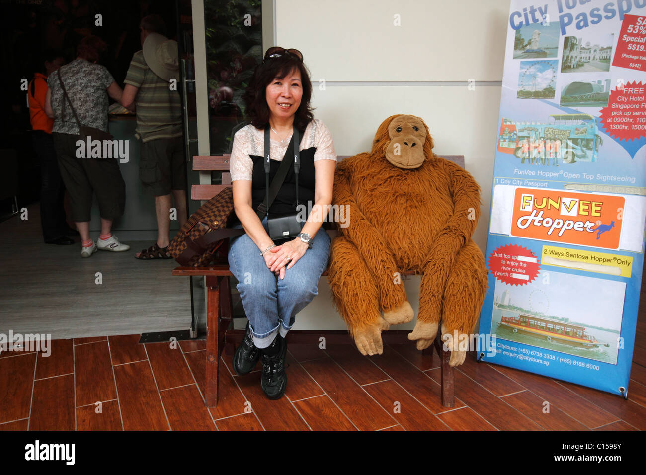 Donna cinese seduta su una panchina accanto a un ape ripiene Foto Stock