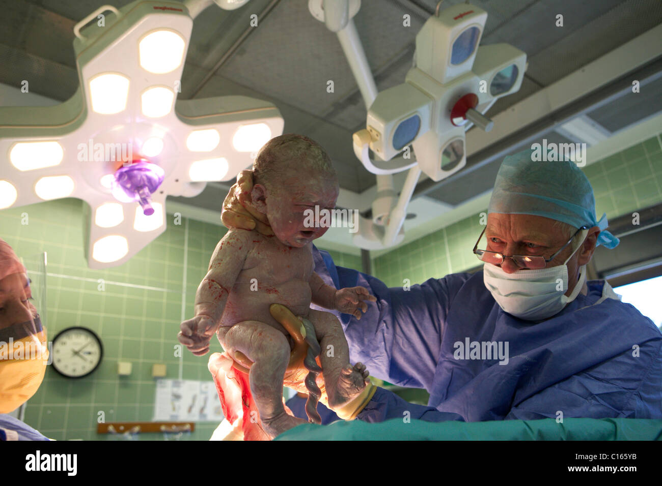 Un ostetrico ginecologo/detiene un neonato come lei prende il suo primo respiro nella camera di mandata. Foto Stock