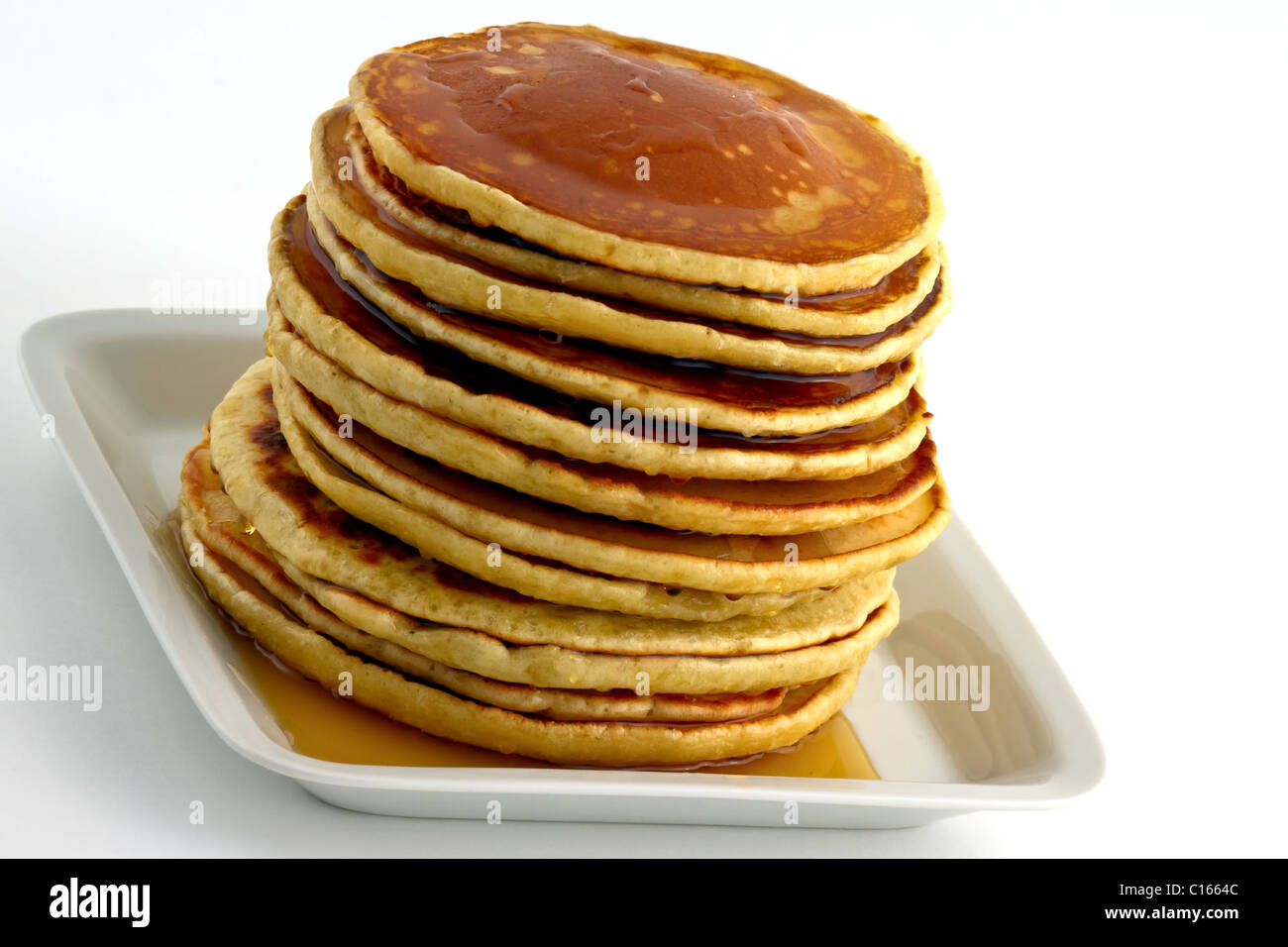 Pila di Pancake fatti in casa con sciroppo su una piastra bianca. Isolato su bianco Foto Stock