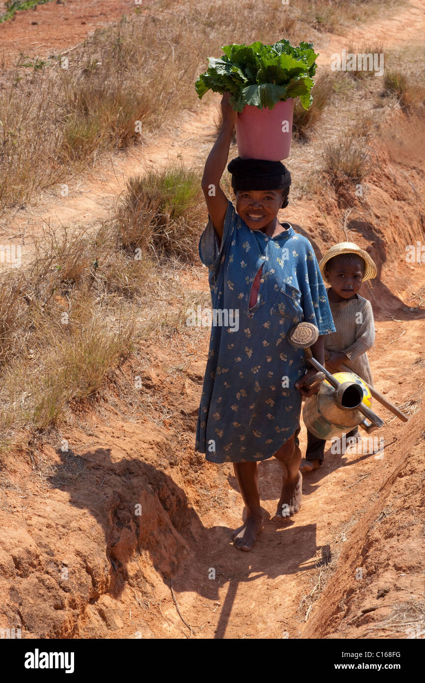 La madre e il bambino portando in ortaggi raccolti dai campi. Nei pressi di Fianarantsoa, Madagascar meridionale. Foto Stock