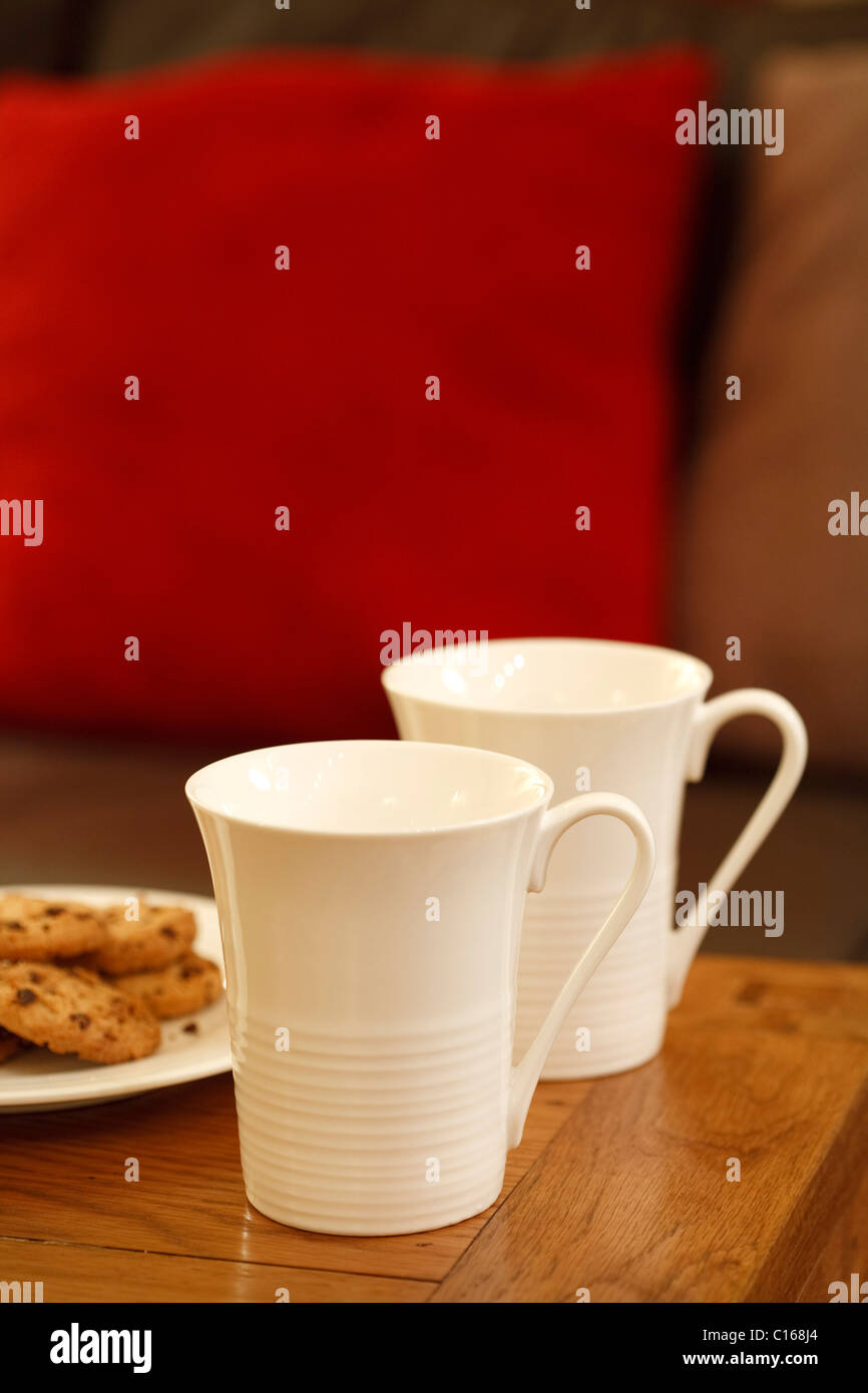 Tazze da caffè e biscotti con copyspace in un moderno soggiorno Foto Stock