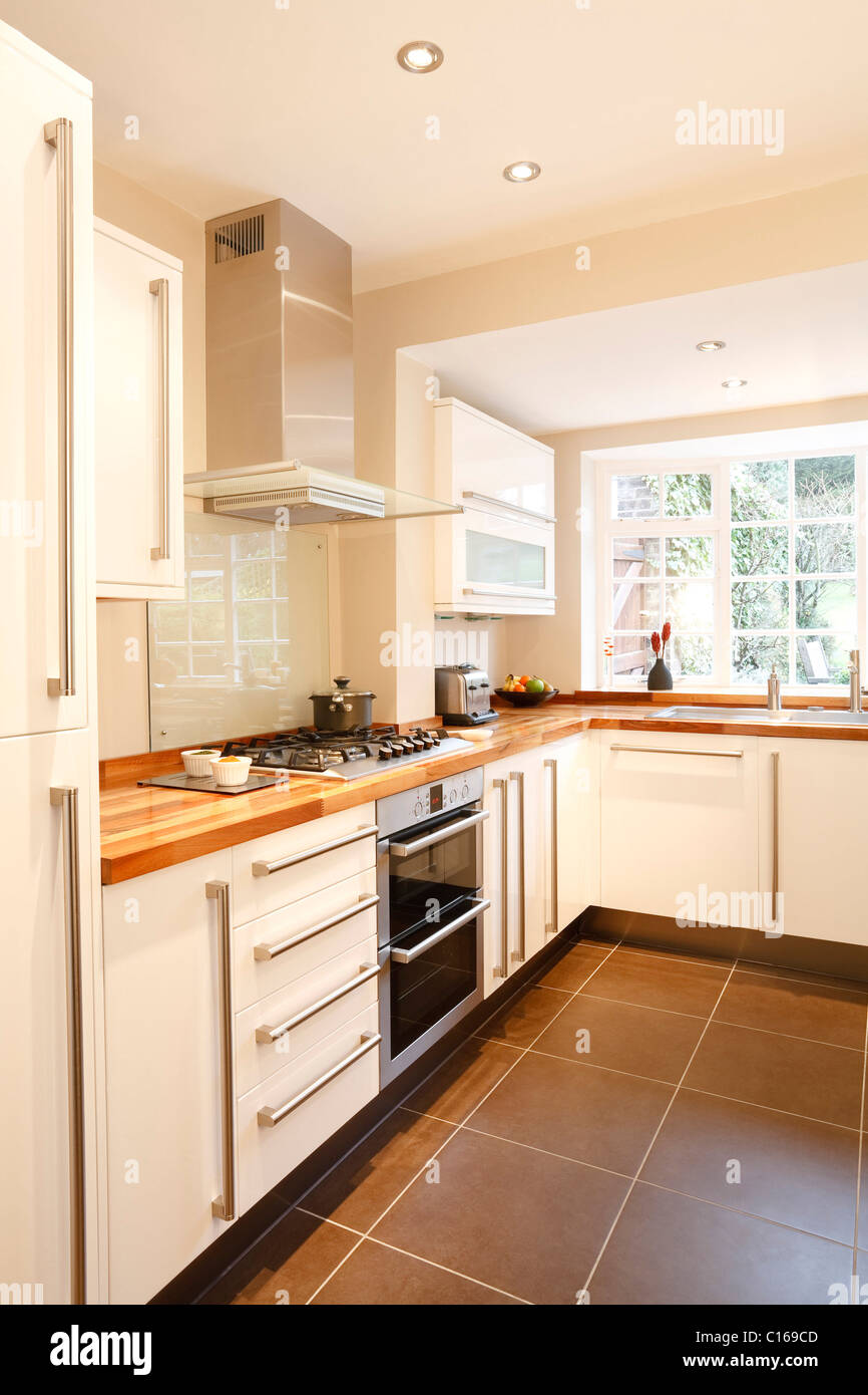 Bianca e moderna cucina con piani in legno e applicazioni in acciaio inossidabile Foto Stock