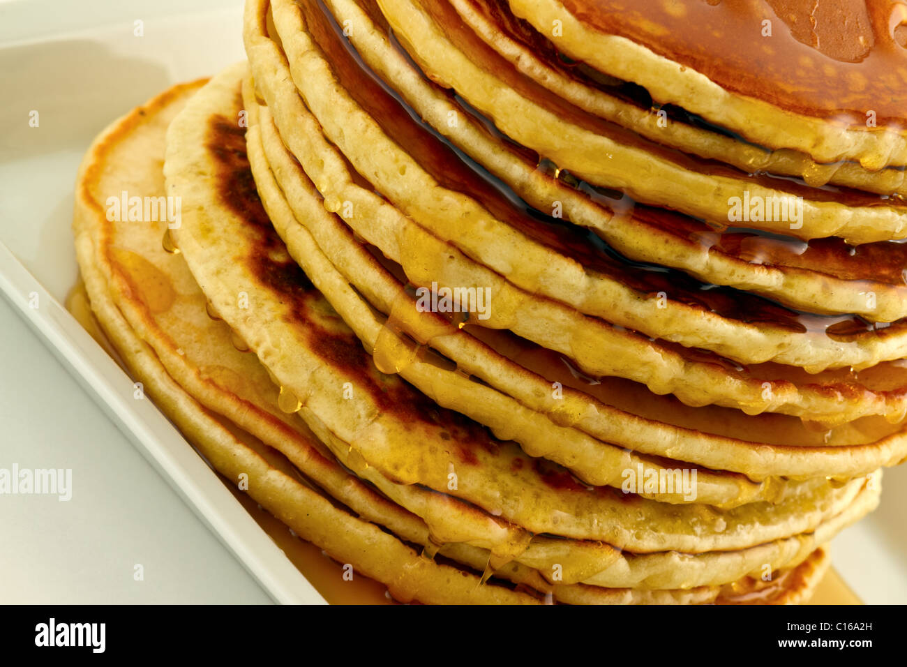Pila di Pancake fatti in casa con sciroppo su una piastra bianca. Foto Stock