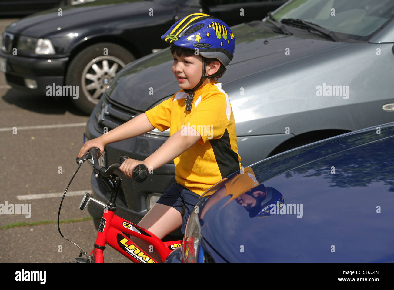 Cinque-anno-vecchio ragazzo che indossa un casco per bicicletta in sella a una moto Foto Stock