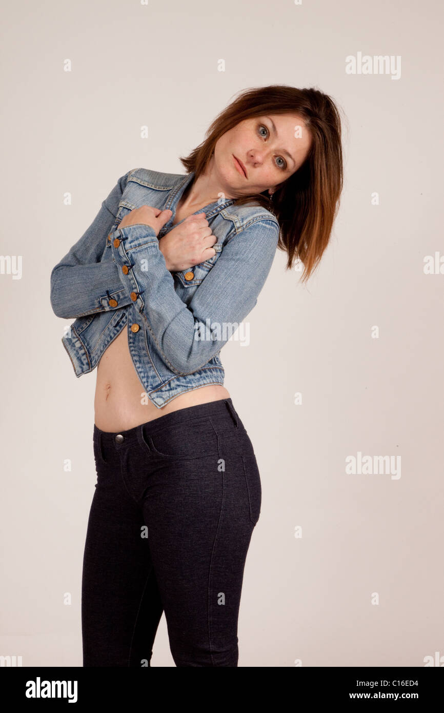 Una bella donna blu jean giacca con le braccia incrociate attraverso il suo torace e grave il contatto visivo Foto Stock