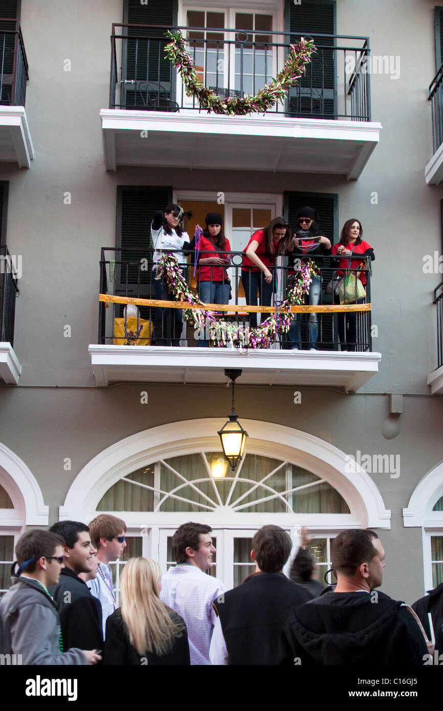 Le donne su un balcone flirtare e gettando Mardi Gras collane fino alla  folla di uomini sotto su Bourbon Street a New Orleans Foto stock - Alamy