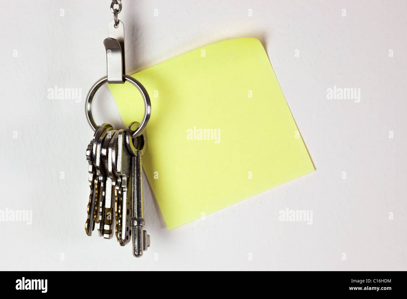 Mazzo di chiavi appesi al muro con una nota adesiva Foto Stock