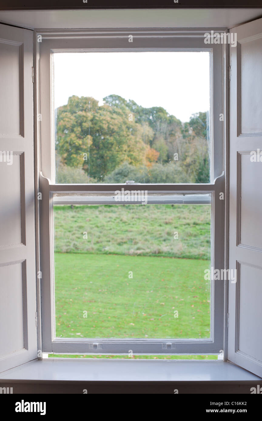 Una vecchia casa colonica finestra con una profonda davanzale si affaccia sul prato, campo e nei boschi vicino a Nenagh, Irlanda. Foto Stock