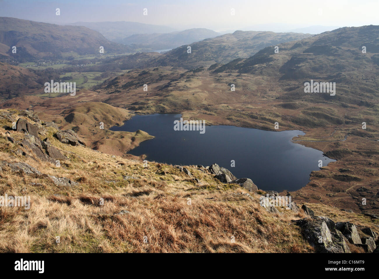 Easedale Tarn visto dalla rupe sopra. La distanza è Grasmere. Lake District inglese. Foto Stock
