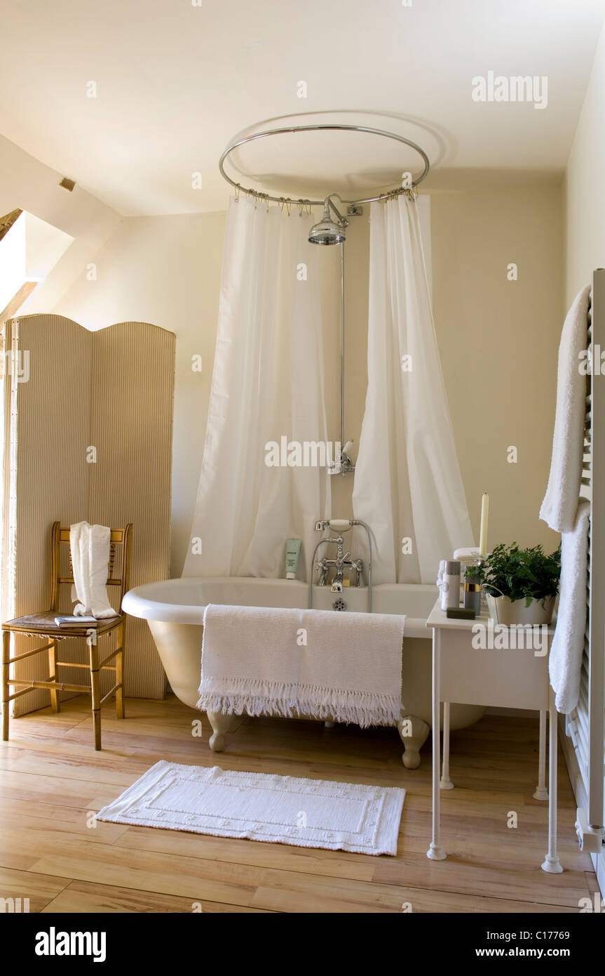 Freestanding roll-top vasca circolare con la tenda della doccia in bagno  con lo schermo a scomparsa e il pavimento in legno Foto stock - Alamy