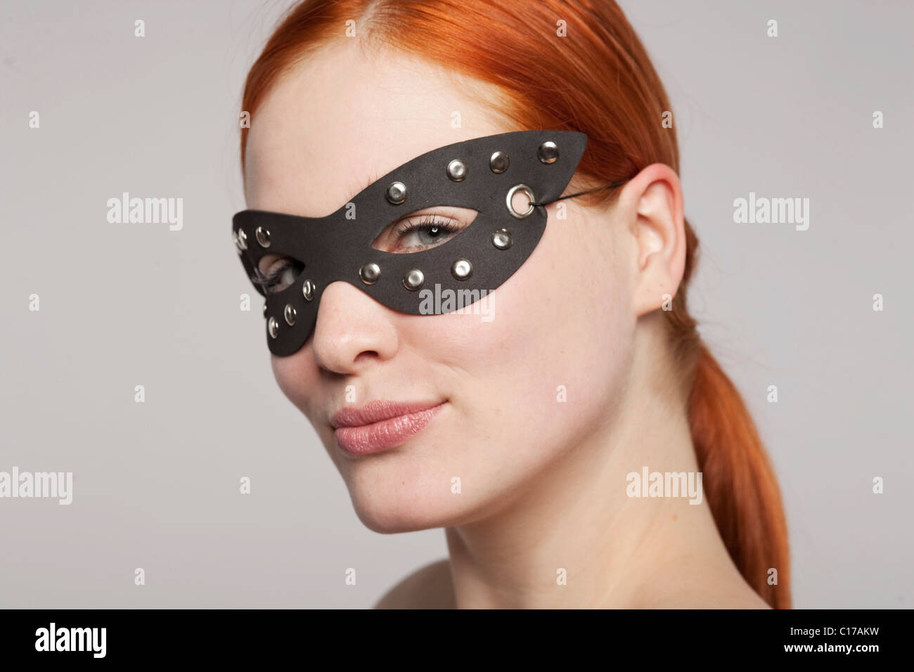 I giovani i capelli rossi donna che indossa un nero maschera in pelle Foto Stock
