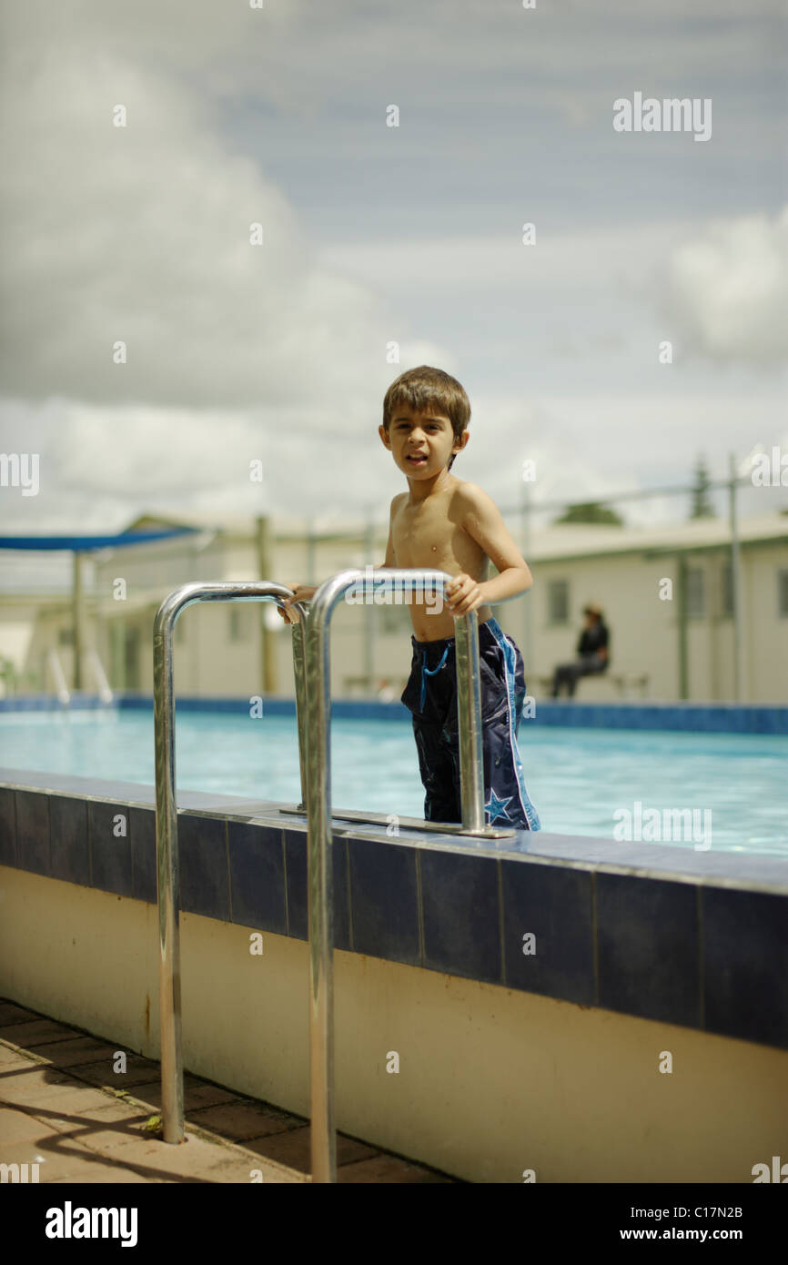 6 anno vecchio ragazzo sorge su fasi come egli esce della piscina. Foto Stock
