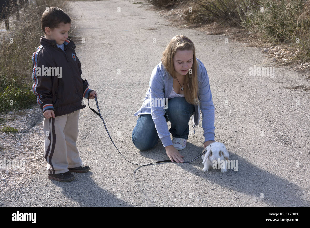 Giovane donna che mostra little boy come andare a piedi il pet baby coniglio in piombo Foto Stock