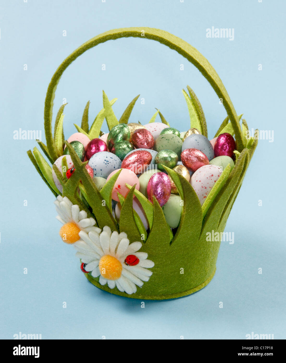 Verde Cesto di Pasqua con uova di cioccolato su sfondo blu. Foto Stock