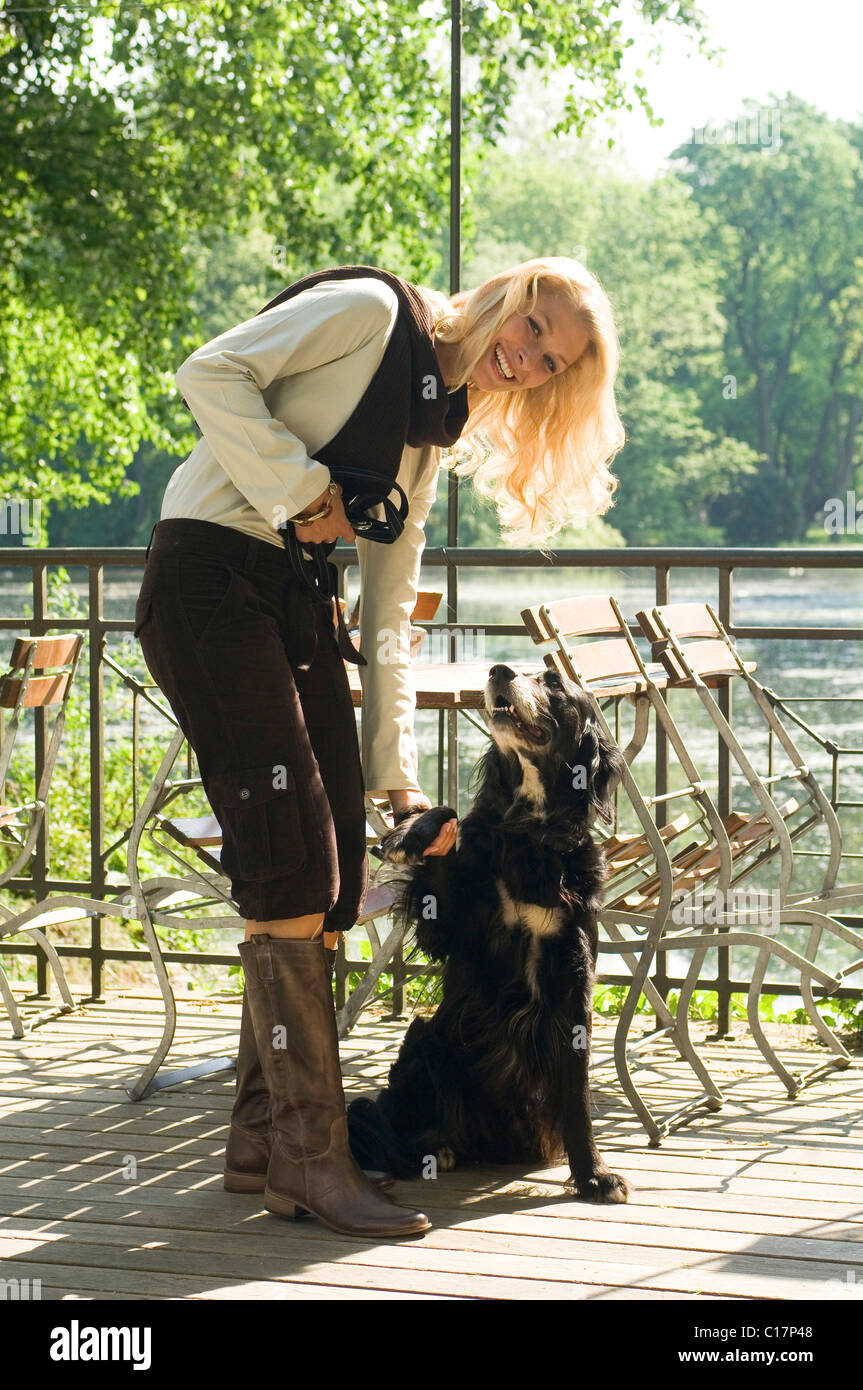 Modello con un cane in un giardino della birra, a un lago Foto Stock