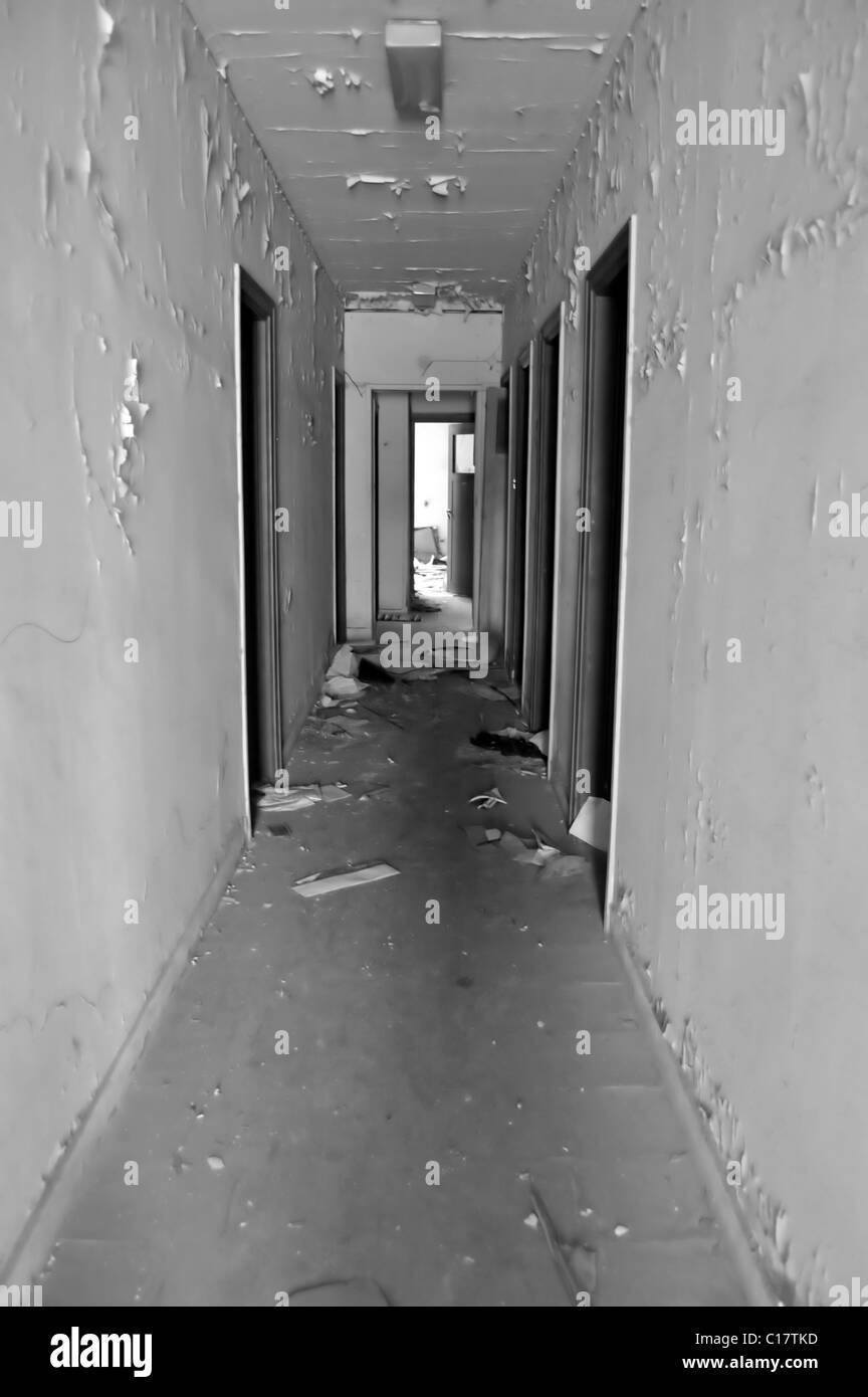 Vuoto lungo il corridoio e porte in edificio abbandonato. In bianco e nero. Foto Stock
