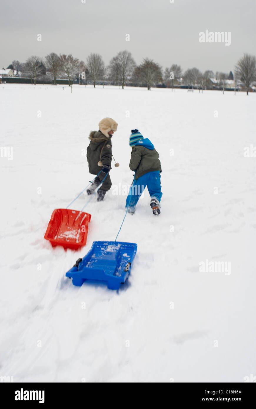 Ragazzi in esecuzione nella neve con le slitte Foto Stock