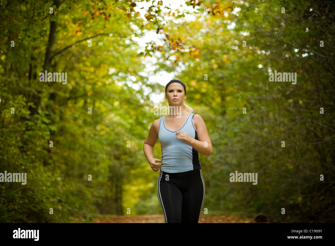 Giovane donna jogging in una foresta autunnale Foto Stock