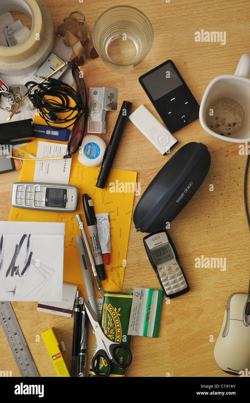 Una vista ortogonale di un confuso desk superficie con tutti i tipi di fermo, elettronica e tazze sporche. Foto Stock