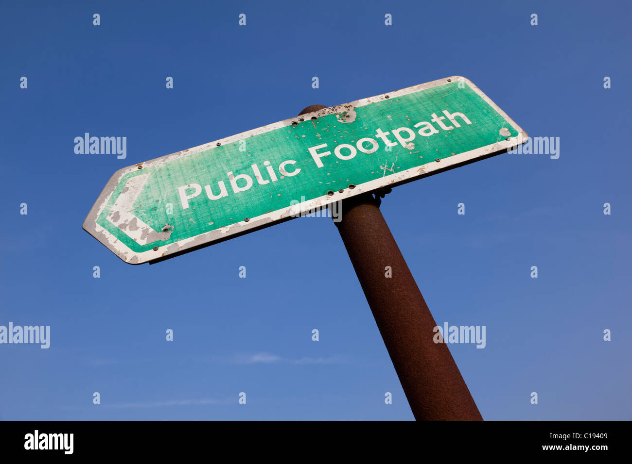 Generic UK sentiero pubblico segno rivolta verso sinistra su un palo arrugginito contro un profondo cielo blu Foto Stock