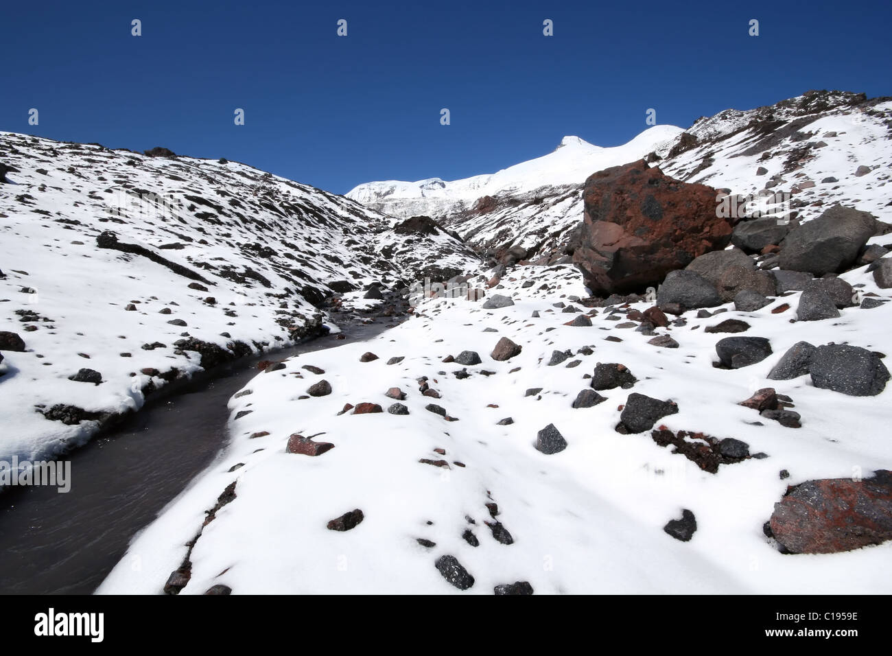 Il fiume del ghiacciaio tra pietre e rocce di neve nelle montagne del Caucaso, area Elbrus, Kabardino-Balkaria. Foto Stock