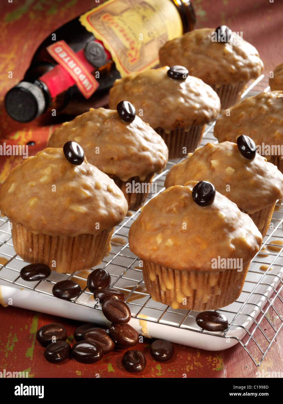 Liquore al caffè muffin su un vassoio guarnito con chicchi di caffè davanti ad una bottiglia di liquore al caffè Foto Stock
