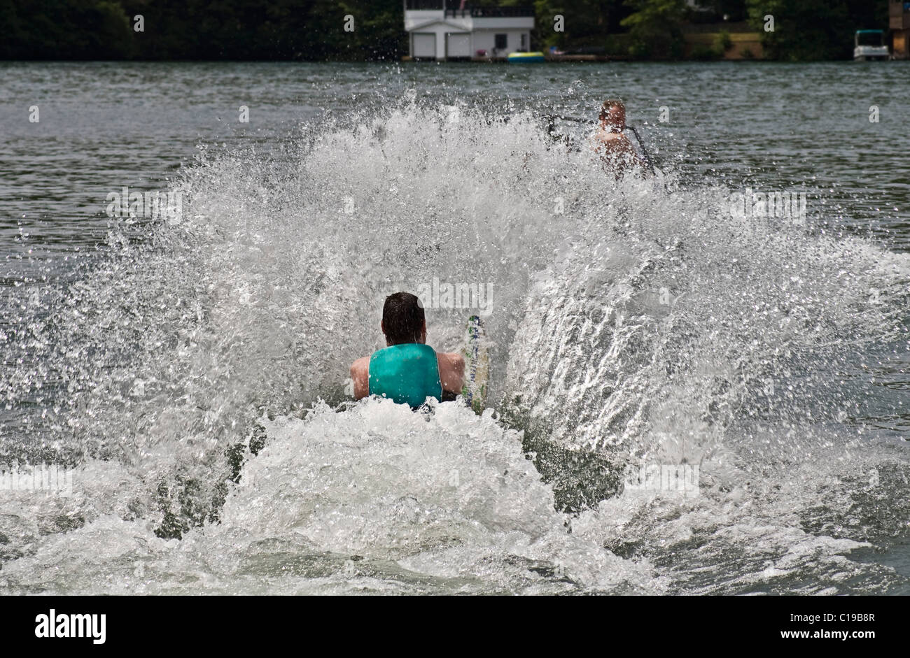 Uomo su uno sci da slalom tirati fuori dall'acqua. Il conducente della barca è appena visibile dietro lo spray. Foto Stock