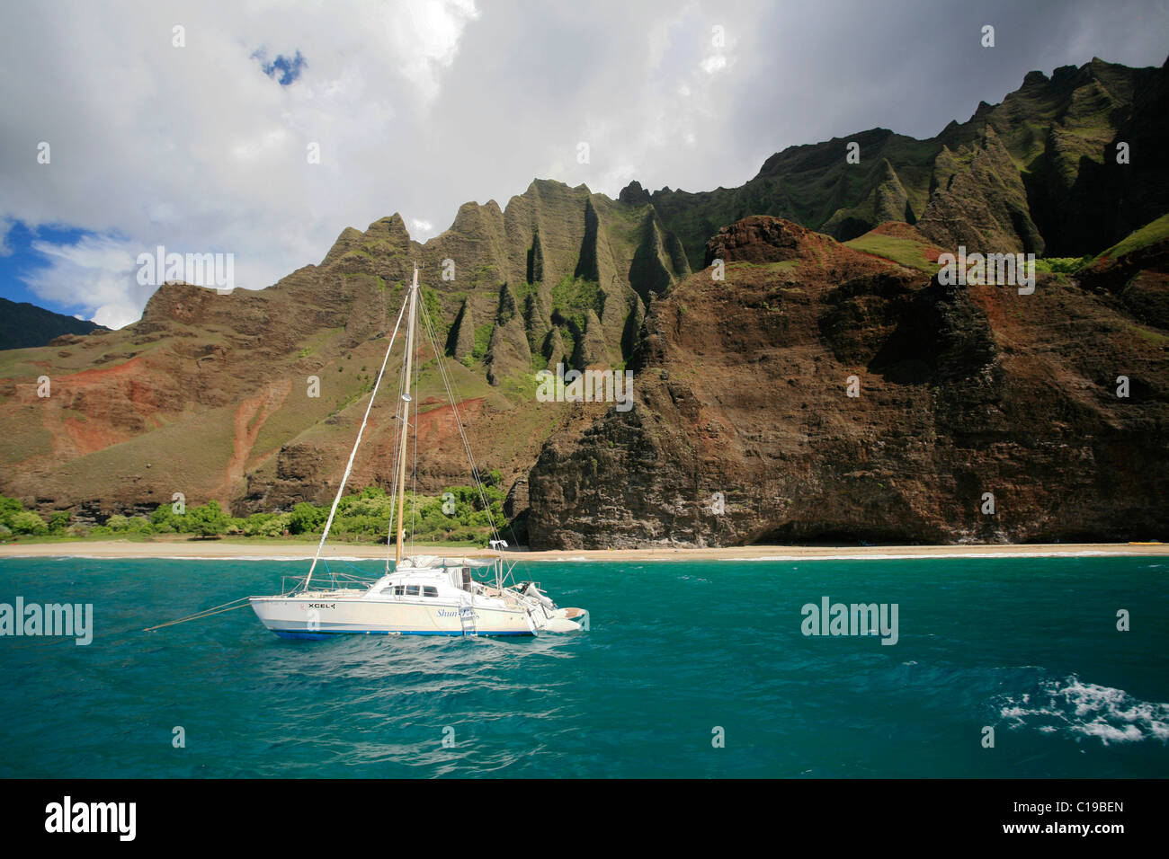 Catamarano a vela nella parte anteriore delle ripide scogliere sulla costa di Na Pali, Kaua'i Island, Hawaii, STATI UNITI D'AMERICA Foto Stock