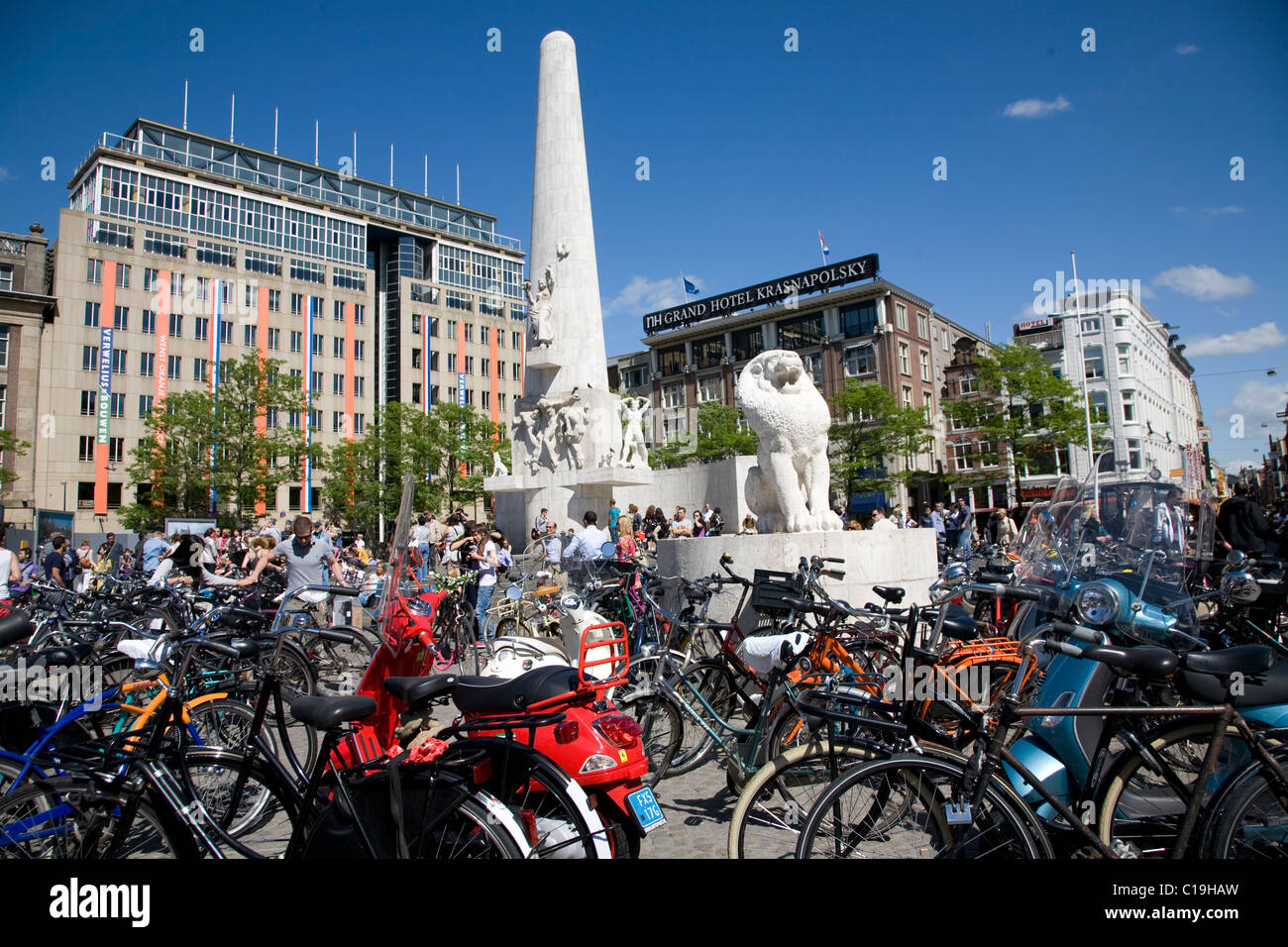 Biciclette in Piazza Dam. Monumento Nazionale, Verwelius e Grand Hotel Krasnapolsky edifici. Amsterdam. Paesi Bassi. Foto Stock
