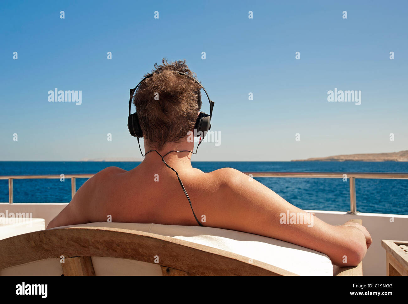 Persona in vacanza relax su una barca mentre si ascolta la musica con le cuffie e guardando a vista Foto Stock