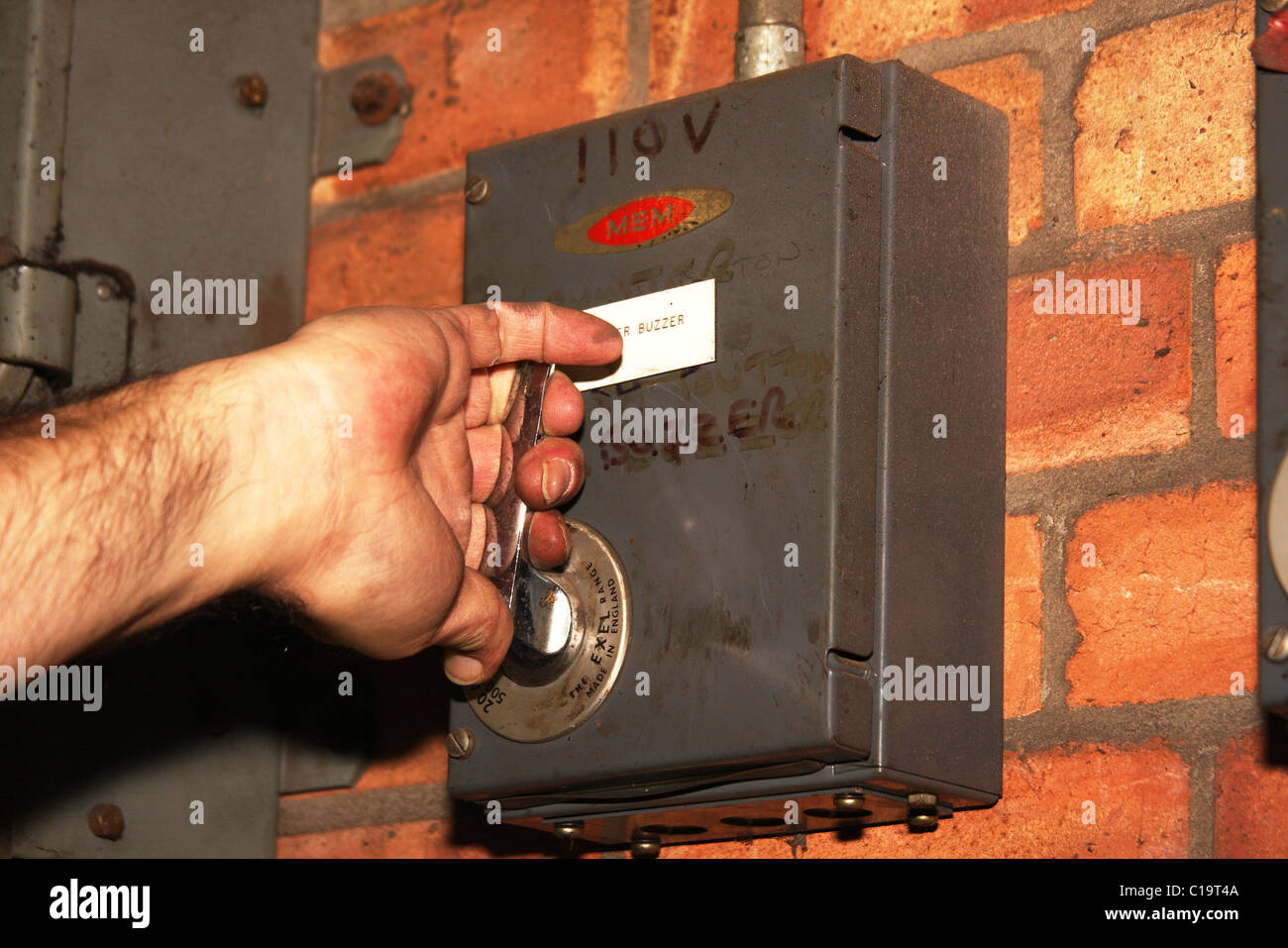 Mano circa per operare a 110 volt interruttore di isolamento. Foto Stock