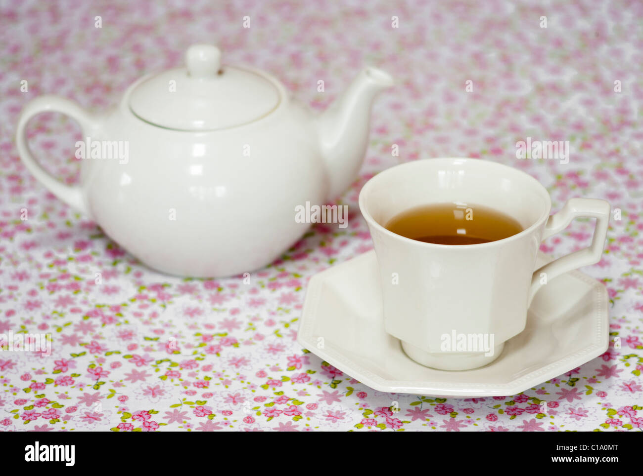 Teiera e tazza di tè su una tovaglia floreale Foto Stock