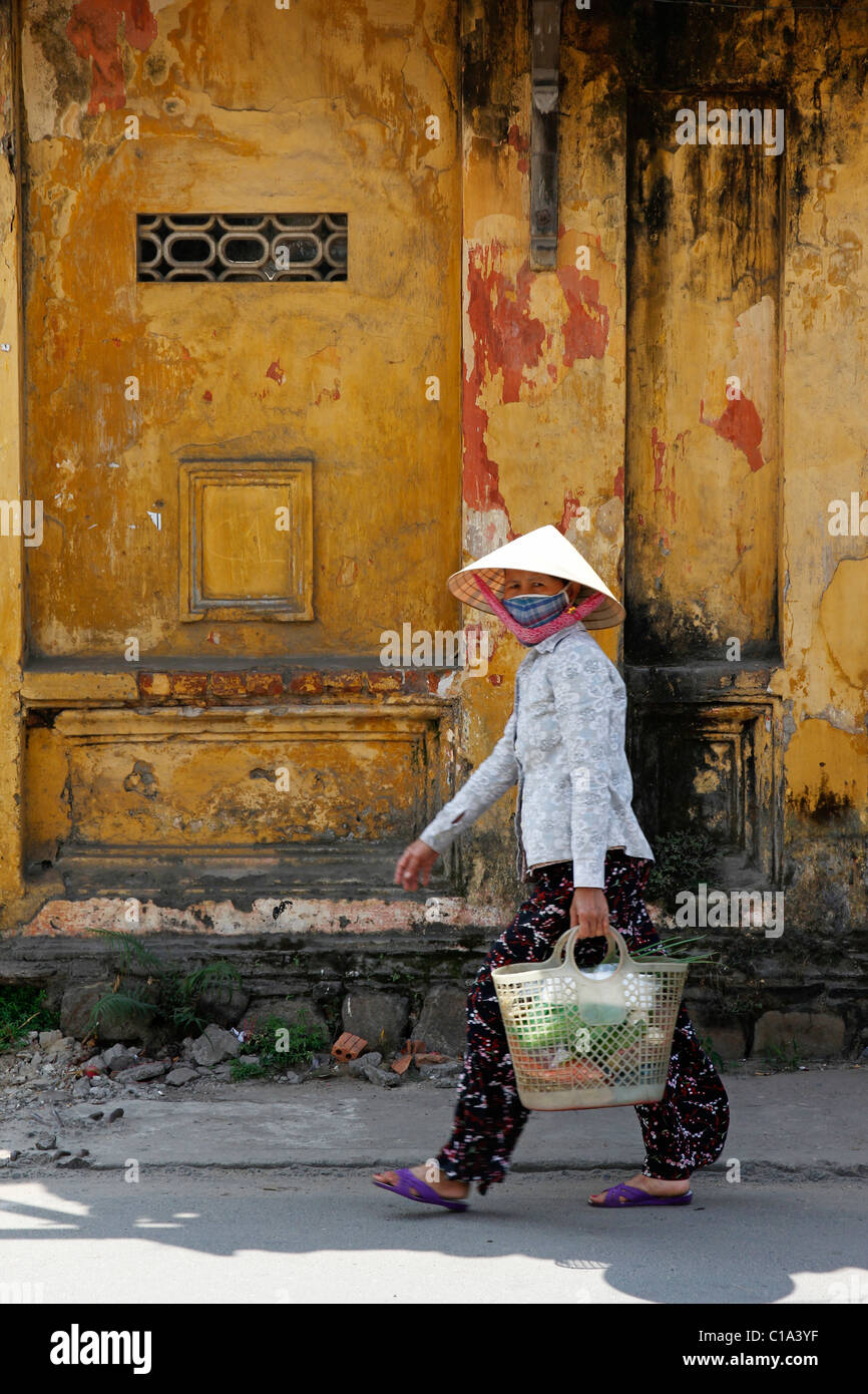 Donna vietnamita che indossa un cappello conico con shopping, Hoi An, Vietnam, Asia Foto Stock