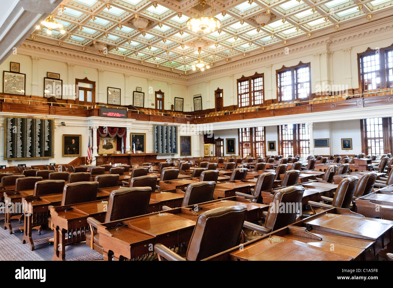 Texas State Capitol House of Representatives Chamber Austin | AUSTIN, Texas — File di 150 scrivanie con schienale in pelle riempiono la camera della Camera dei Rappresentanti del Texas, illuminata da un soffitto a cassettoni dorato risalente al completamento del Campidoglio nel 1888. Progettata dall'architetto Elijah E. Myers, la camera è il fulcro di una legislatura che si riunisce in sessione regolare solo per 140 giorni ogni due anni, uno dei calendari più restrittivi di qualsiasi governo statale. Foto Stock