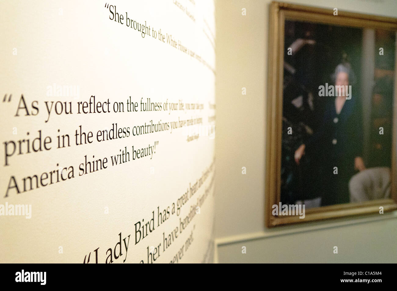Muro di citazioni omaggio di Lady Bird Johnson alla Biblioteca LBJ | AUSTIN, Texas — Una citazione omaggio sul muro curvo della mostra di Lady Bird Johnson alla Biblioteca LBJ recita: "Mentre rifletti sulla pienezza della tua vita, puoi essere orgoglioso dei contributi infiniti che hai dato per aiutare l'America a brillare di bellezza," attribuita a Ronald Reagan. La legge sull’abbellimento delle autostrade di Lady Bird e la sua fondazione di quello che oggi è il Centro Floreale Selvatico Lady Bird Johnson hanno definito un'eredità di conservazione che è sopravvissuta alla presidenza di suo marito. Foto Stock