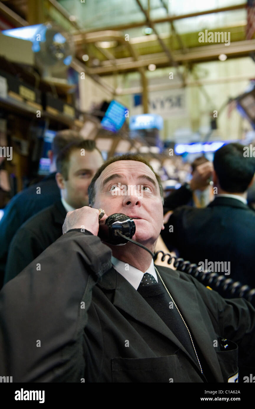 Un commerciante di valori mobiliari guarda ansiosamente a schermi intorno a lui durante la chiamata in un ordine. Foto Stock