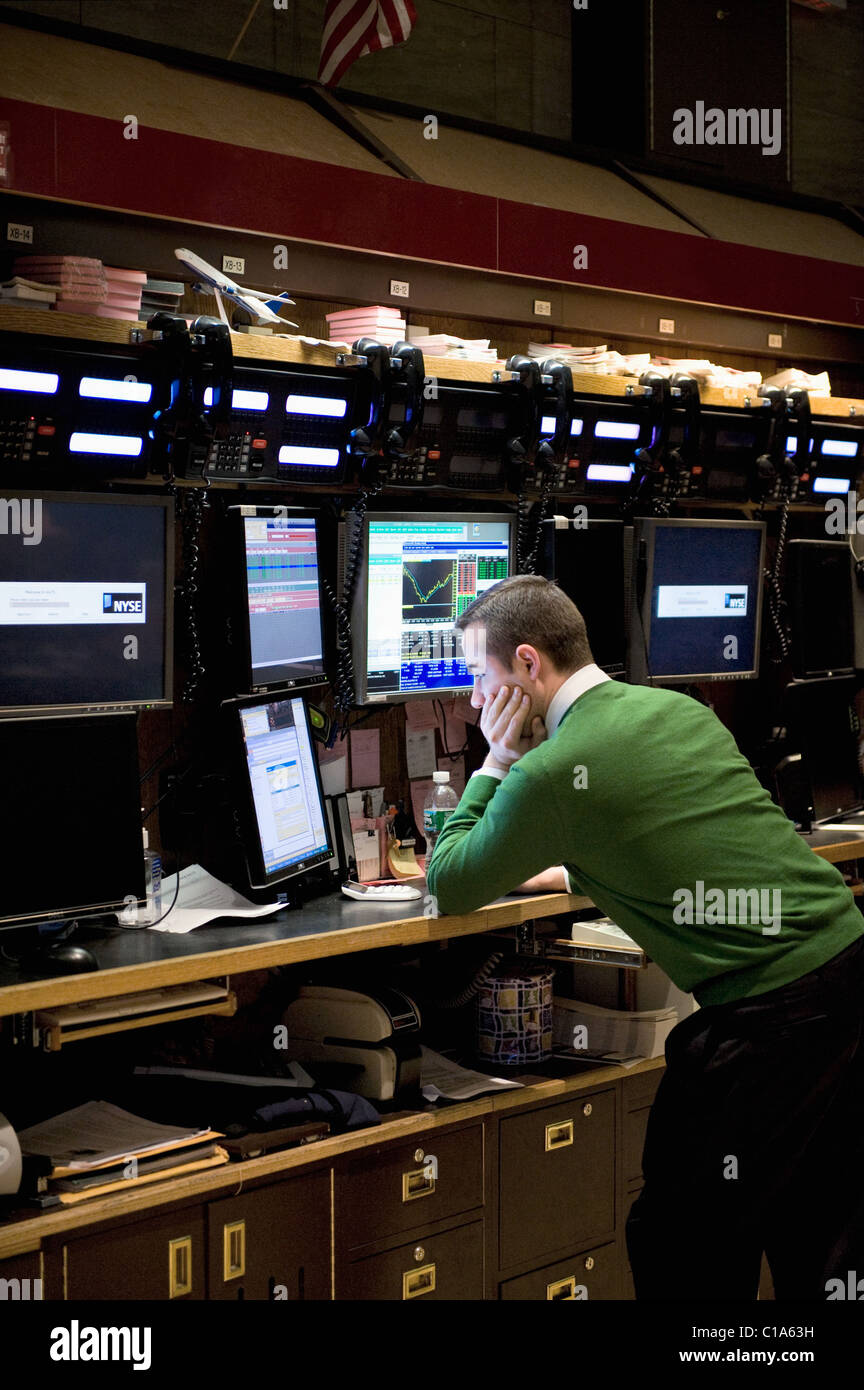 Un uomo sul pavimento del New York Stock Exchange guardando i numeri sul monitor di un computer. Foto Stock