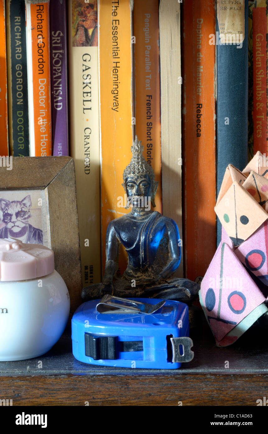 Scaffale con libri & Buddha in plastica flessometro foto piccola vasetto di crema e del bambino puzzle di carta Foto Stock