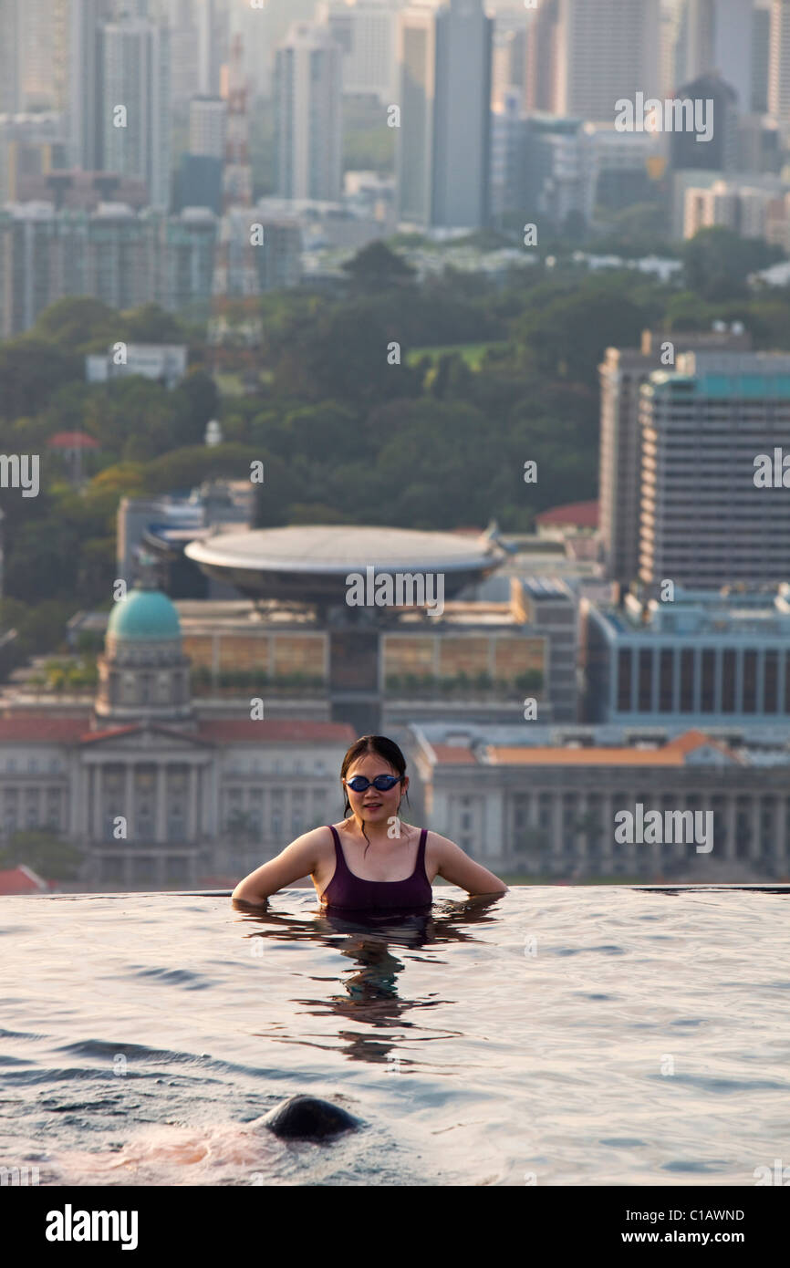 Donna di nuoto in piscina presso il Marina Bay Sands SkyPark con lo skyline della città in background. Il Marina Bay, Singapore Foto Stock