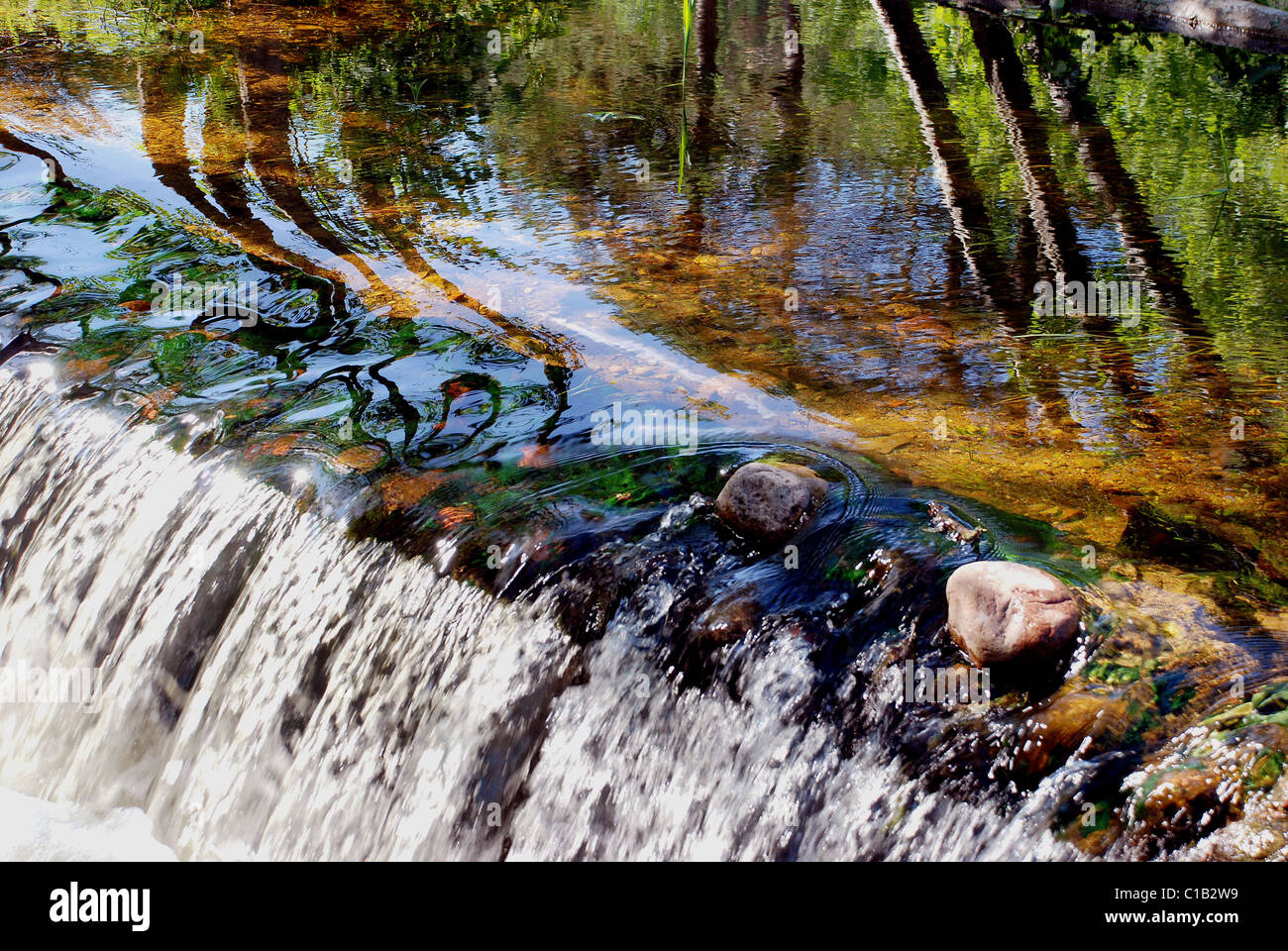 Meraviglioso il flusso del fiume di una piccola cascata e bellissimi riflessi sull'acqua Foto Stock