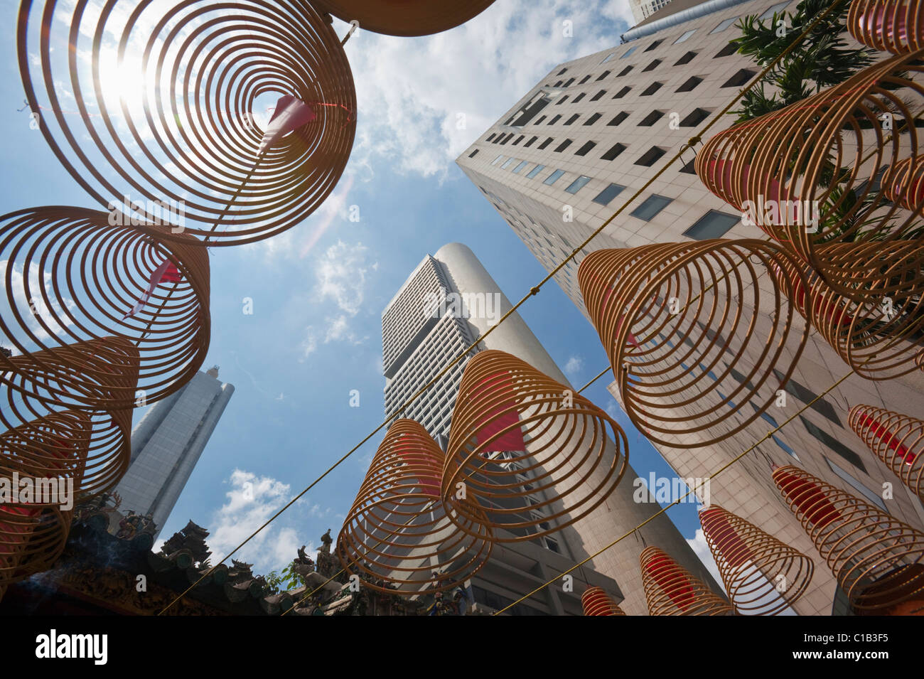 Incenso a spirale con spire dello skyline della città in background in Wak Hai Cheng Bio tempio, Raffles Place, Singapore Foto Stock