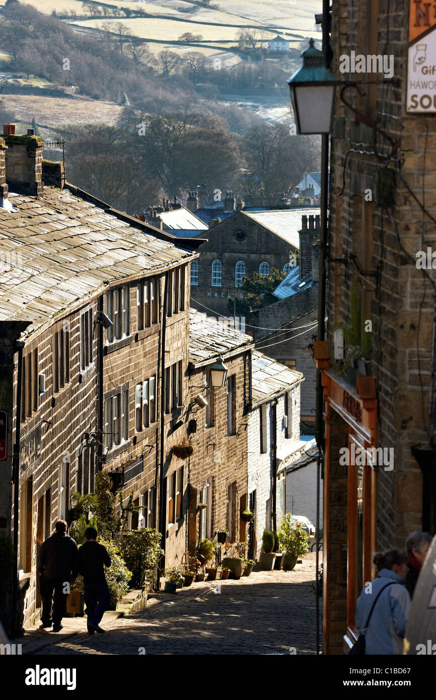 Haworth, West Yorkshire, guardando giù per la strada principale lastricata in pietra, l'inverno. Foto Stock
